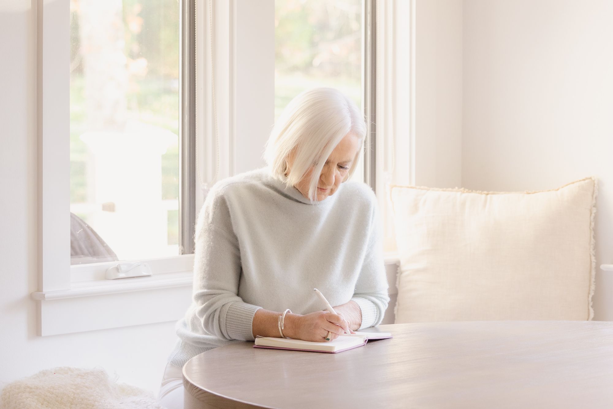 Catherine Taylor Hickem writing at a table by the window